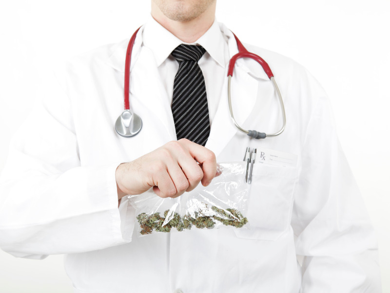 Medical doctor wearing white coat holding a bag that contains marijuana.